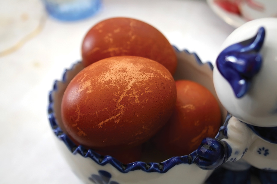 Red Easter eggs, dyed with onion, in a vintage ceramic bowl. Selective focus.