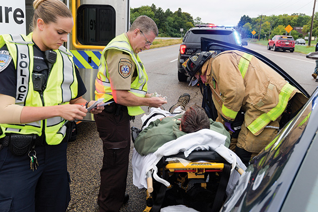 Maddy working a crash scene with an HCMC paramedic and an Excelsior Fire District firefighter before the victim is transported.