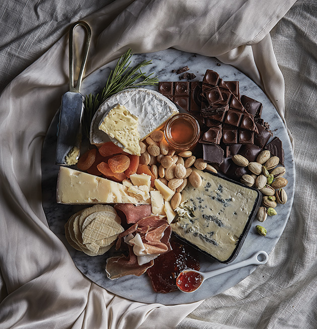 A spread of cheese, chocolate, fruit and nuts.
