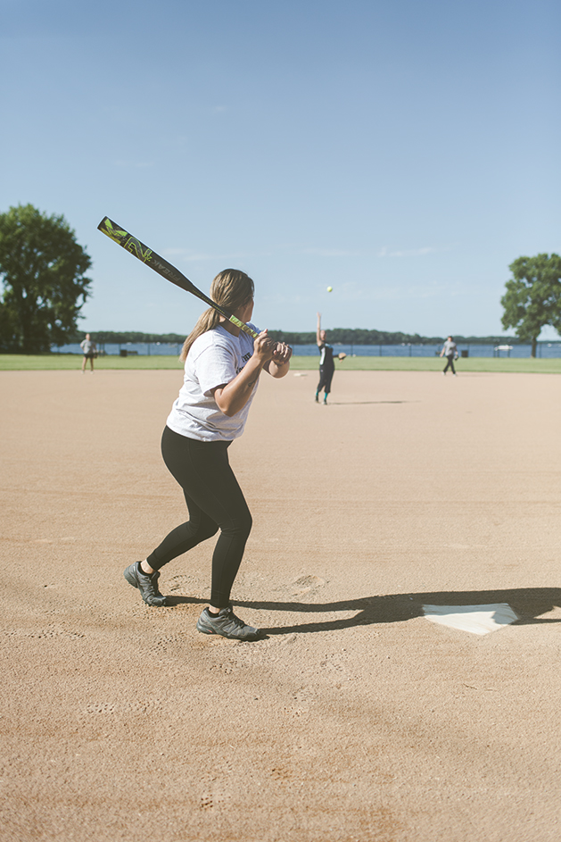 Woman taking a swing at a softball.