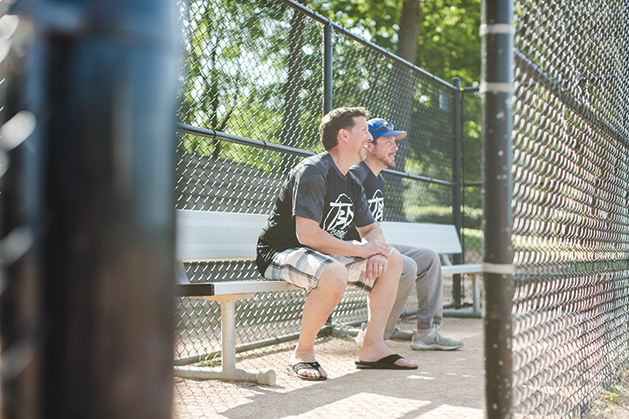 Two men watching the South Shore Softball League playing.