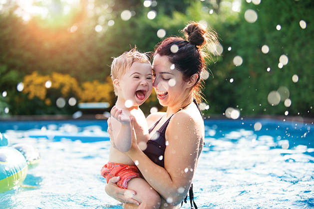 A woman holds a child in a pool.