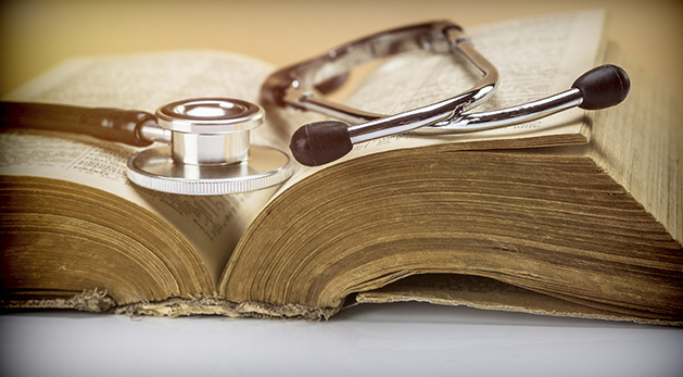 An old stethoscope sits on an old medicine book.