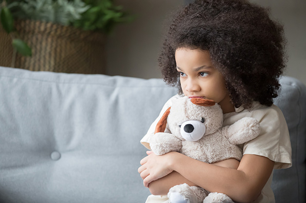 A stressed child holds a teddy bear.