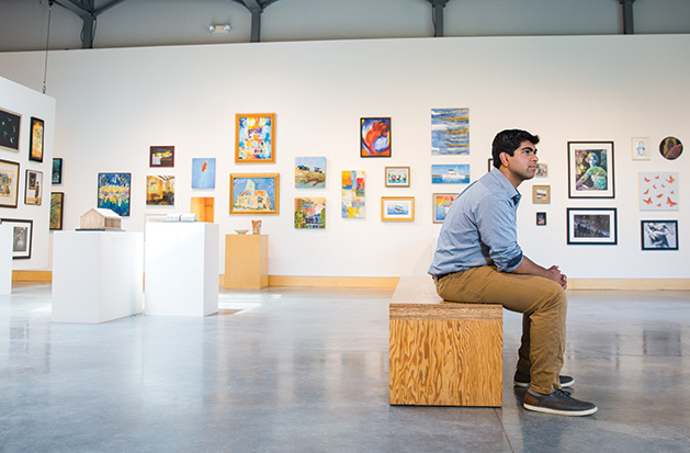 Jai Chadha, part of the 2019 Senior Spotlight, sits in front of a wall of art.