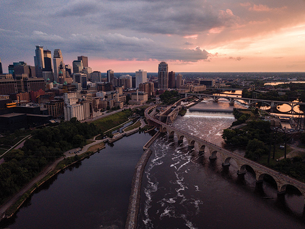 A shot of the Minneapolis skyline at sunset, with the Stone Arch Bridge in the foreground.
