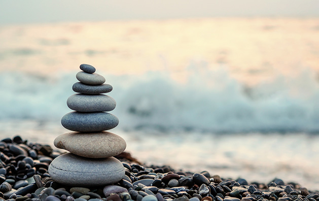 A stack of balanced rocks on a shoreline, a metaphor for achieving a balanced life.