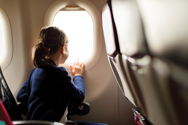 A girl looks out a plane window on a family vacation.