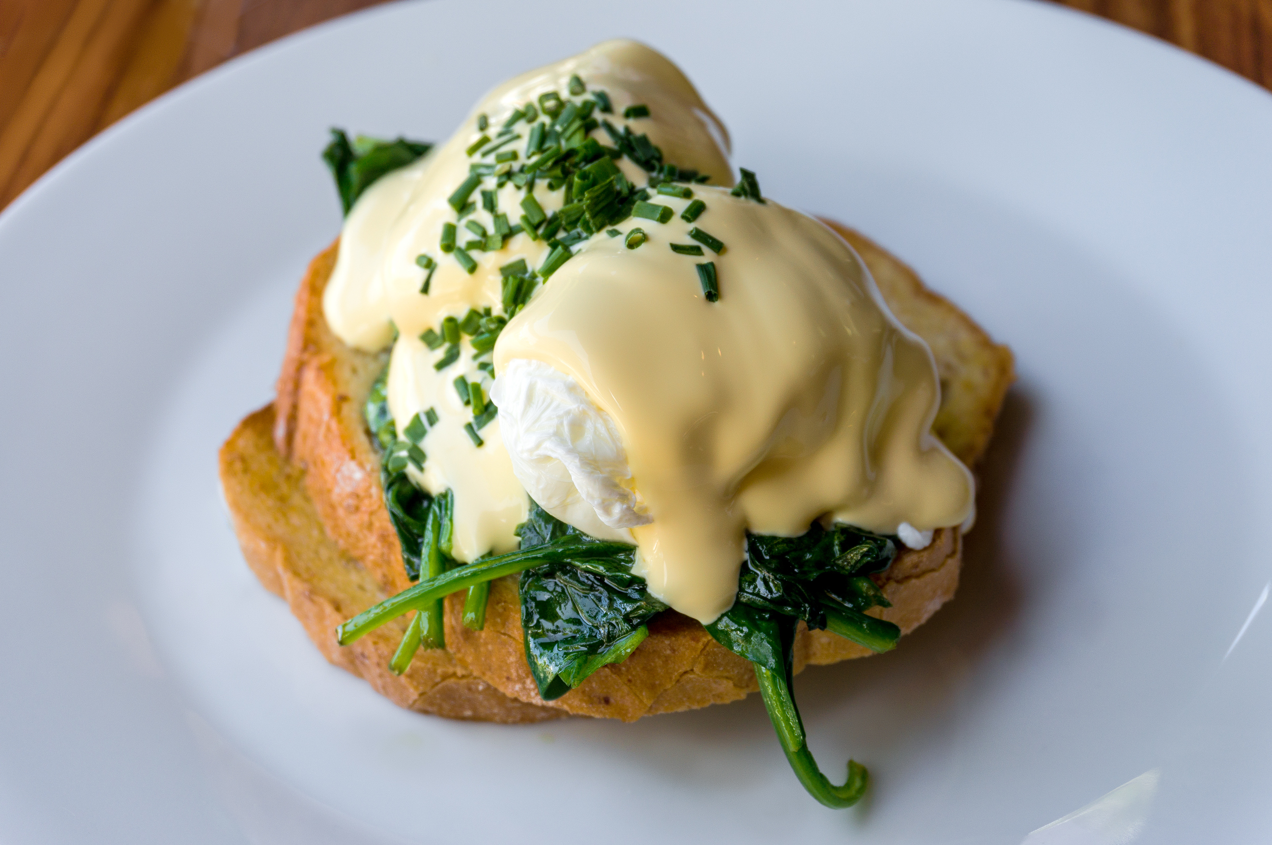 Eggs Benedict with spinach on toast. Poached egg on toast with spinach and chives on white plate. Healthy breakfast. Selective focus, shallow dof