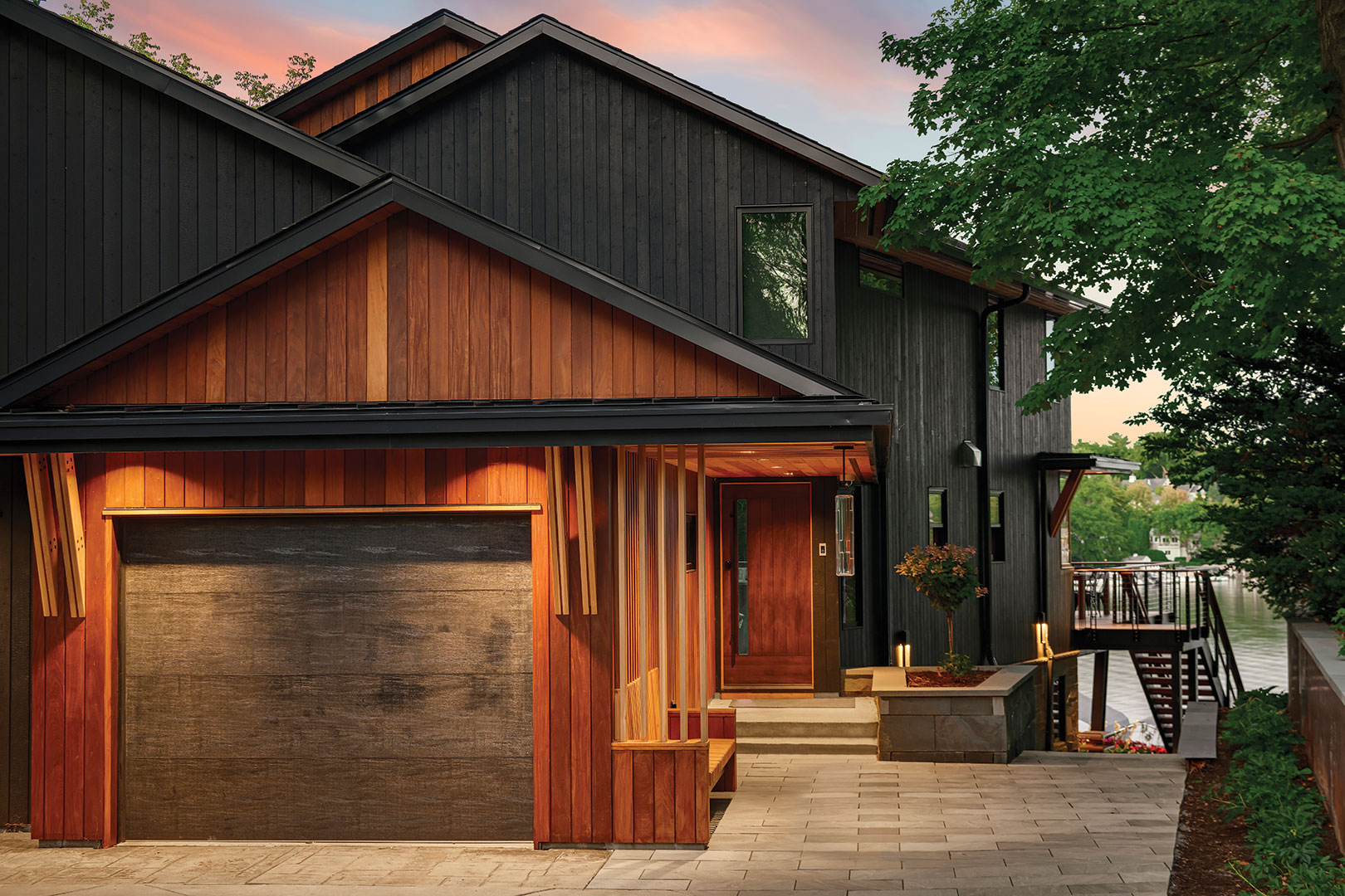 Brazilian walnut—like the kind used for the home’s flooring and decking—was milled by the Boyer carpenters into a shiplap profile to create the home’s rustic and durable siding. They also created an integrated wooden bench and warm lighting next to the front walkway, where guests can see one last view of the lake before catching a ride to their next destination.