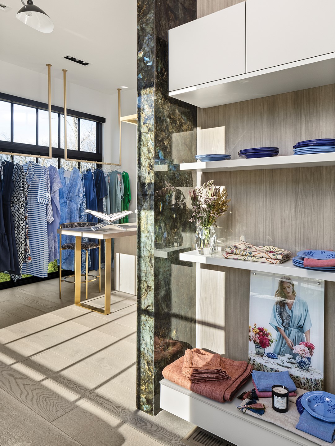 In addition to suites for visitors, the guest house also hosts the homeowner’s showroom for her fashion designs, making use of the large windows for plentiful natural light and efficiently designed storage spaces. Gold-toned, minimalist hanging racks in front of the windows let the colorful clothing shine, and the feature wall is made from the semiprecious stone labradorite. “Our main intention for this space was to make this interior unique,” says Payares. “The stone mostly has deep green tones with touches of blue. Our client loves those two colors, so when we presented the stone selection, she wanted to use it in the guest house. This specific space was designed for her own use, so we decided this stone would be perfect.”