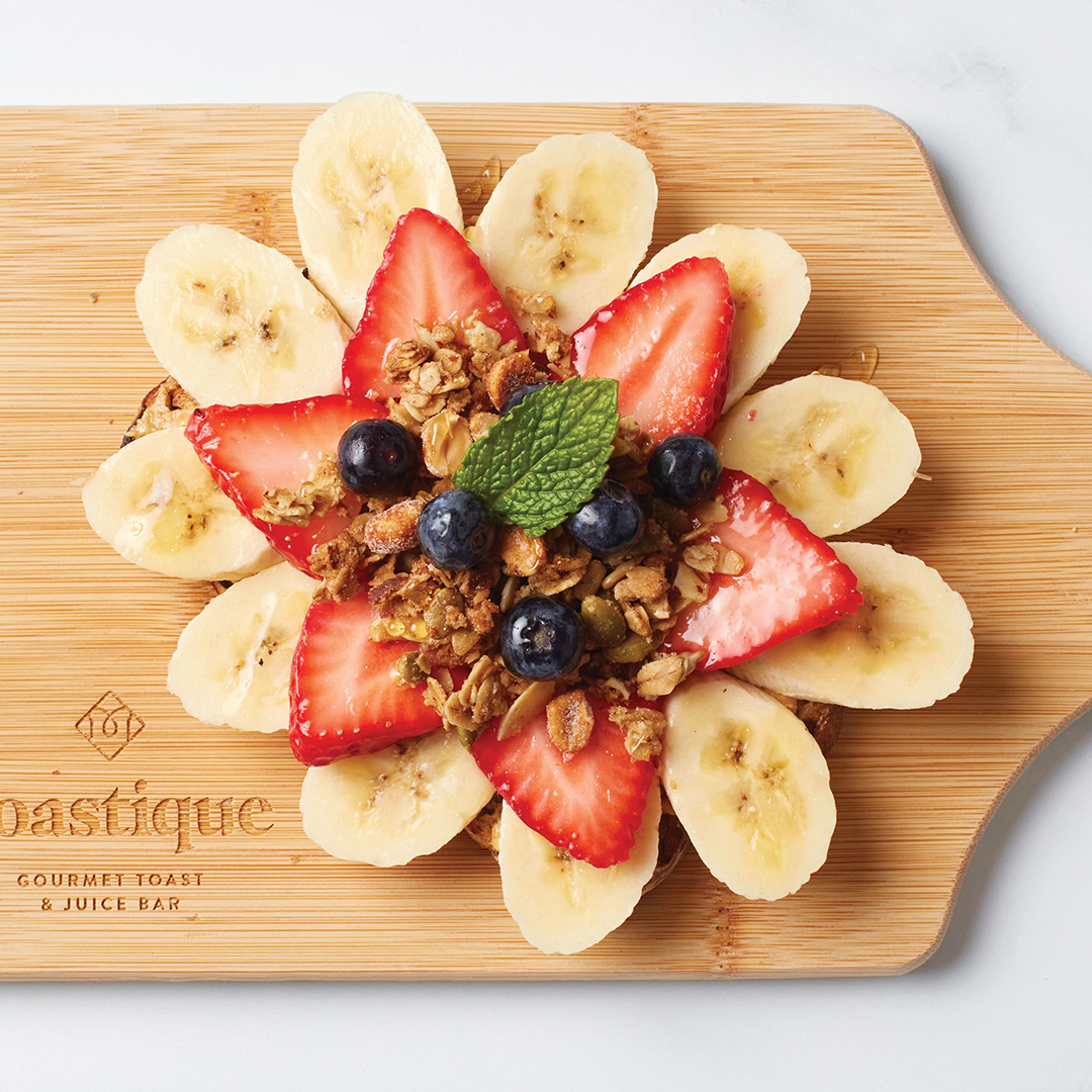 B Crunch hits with honey roasted peanut butter, bananas, strawberries, blueberries, berry jam, granola, peanuts, honey drizzle and mint on walnut raisin toast.