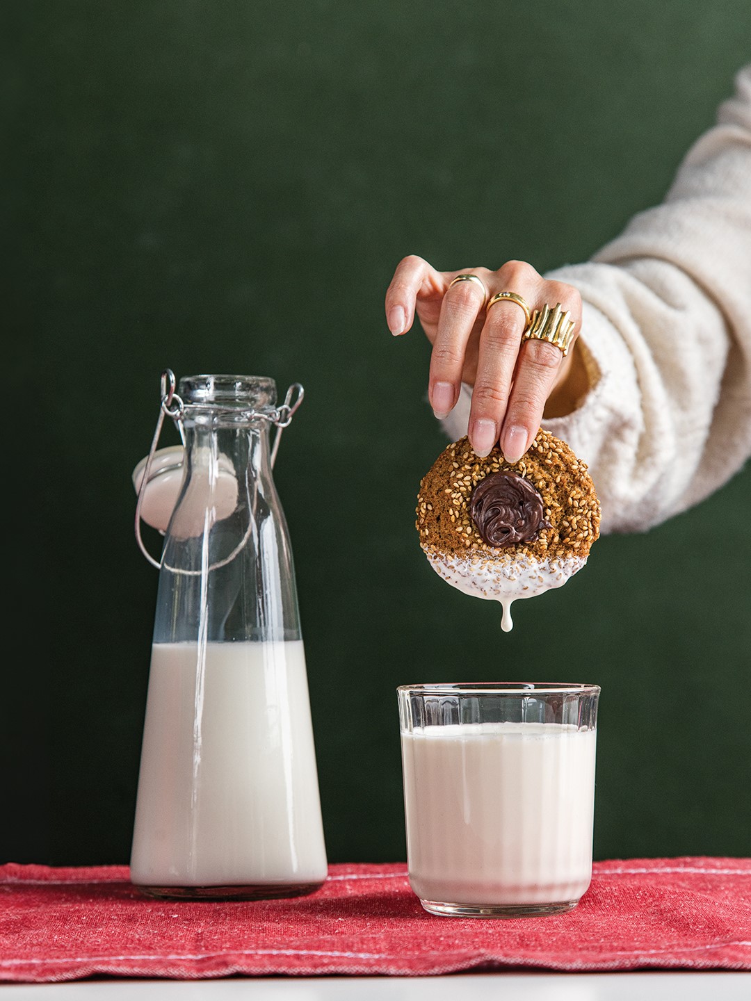 Hand dipping a cookie in a glass of milk