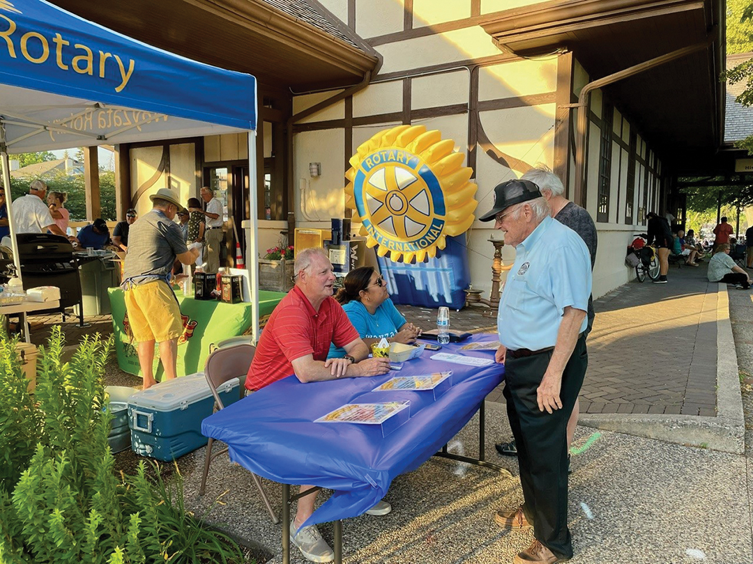 Rotarian Mark Lauffenberger talks with a longtime Depot Museum volunteer during Music by the Lake.