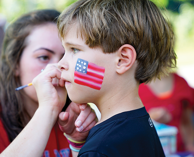 Young boy getting his face painted for 4th of July.