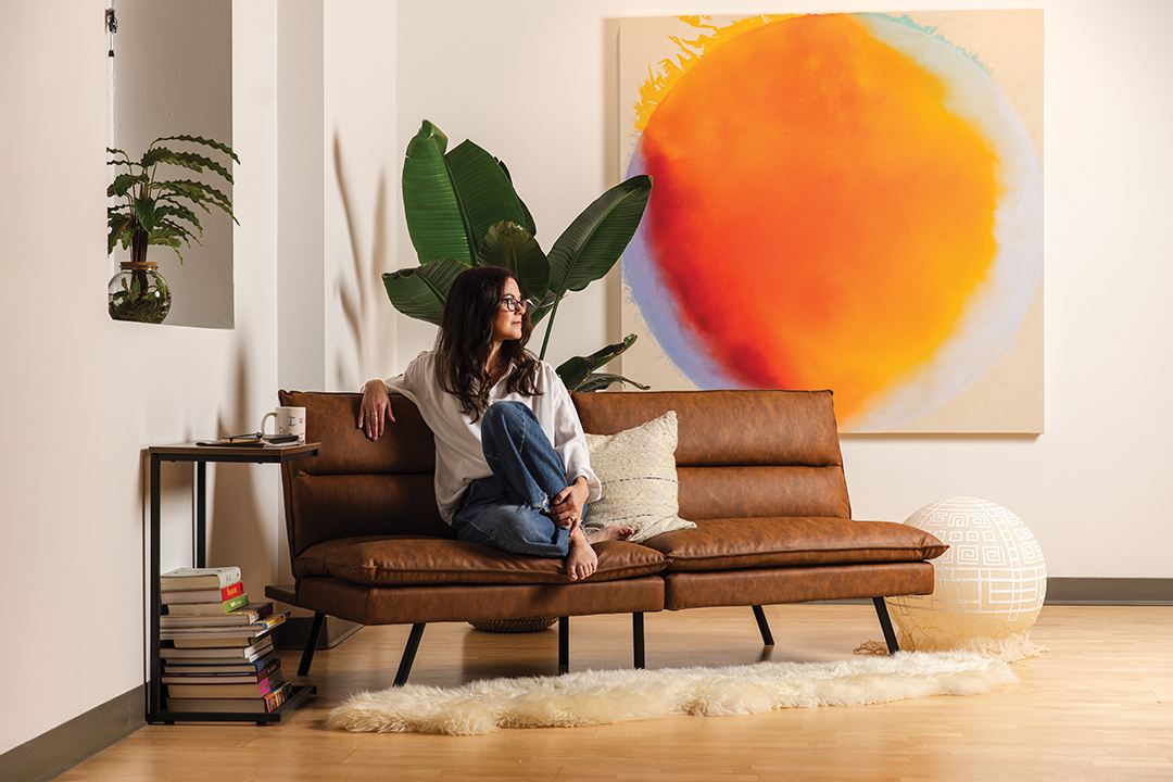 Laura Rockhold sits before the painting RENEWAL. Minneapolis’ Veronique Wantz Gallery will exhibit some of her original poetry and paintings.