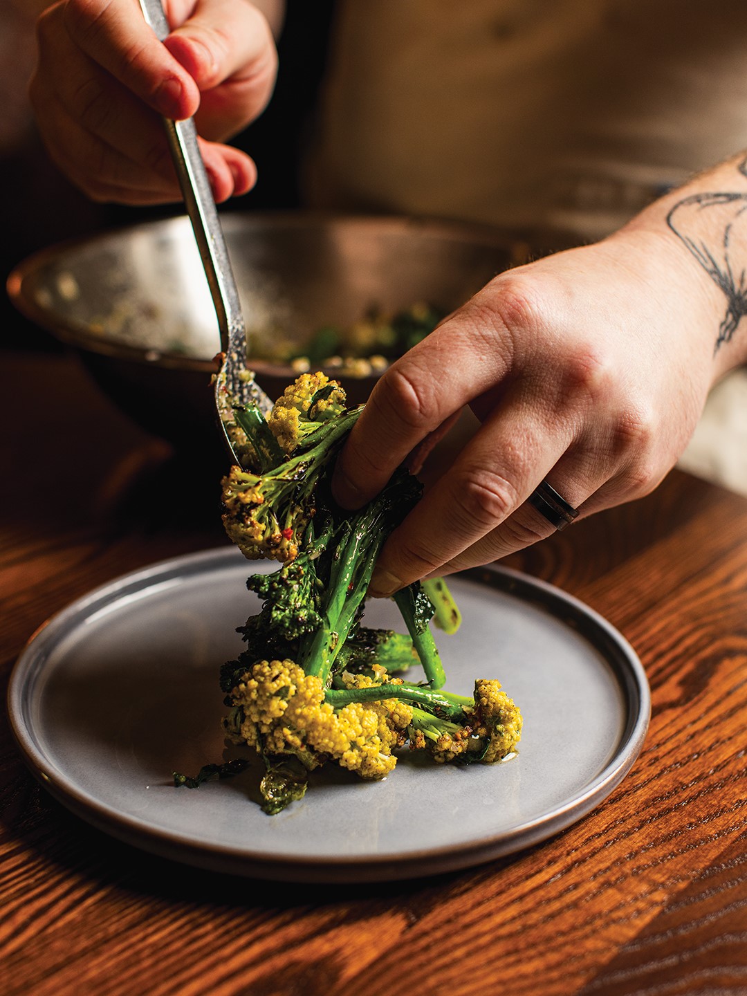 Chef Sam Gilman plating Grilled Brassicas