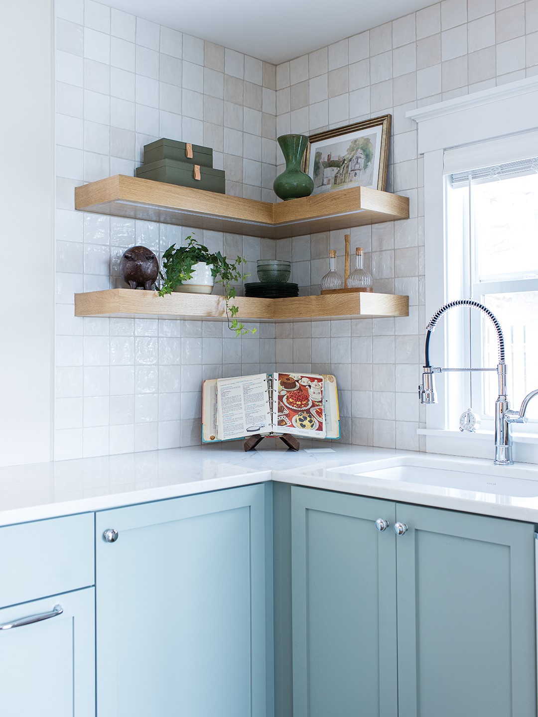 The kitchen features modern appliances with vintage styling that complements two different backsplash tiles (a classic square and a patterned green). “One of my favorite things about the remodel is that we opened up the kitchen entry, and we mimicked another arch that was already existing. It’s just so cute. It has soft lines,” she says. Homeowner Annie Tursi adds, “The team matched the arch perfectly, and it completely changed the feel of the house.”
