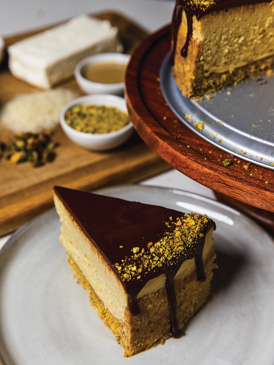 Slice of Dubai Chocolate Cheesecake with ingredients nearby