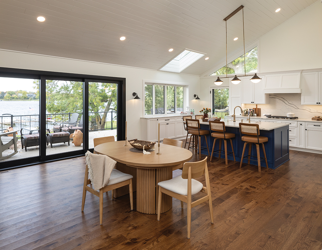 This stunning transformation honors the home’s deep family roots by evolving its 1960s midcentury bones into a bright, transitional sanctuary centered on the lake view. By finishing the original vaulted cedar ceilings in white enamel and adding strategic skylights, the space was modernized into an airy, light-filled hub that reflects the water just beyond the windows, according to Kimberly Fletcher, lead designer at Boyer Building Corporation. The redesigned layout features a curated palette of crisp whites, soft blues and stone quartz countertops with wave-like movement, she notes. The navy blue island serves as the kitchen’s central anchor and a fold-down bar at the window, creating a seamless indoor-outdoor serving connection perfect for entertaining.